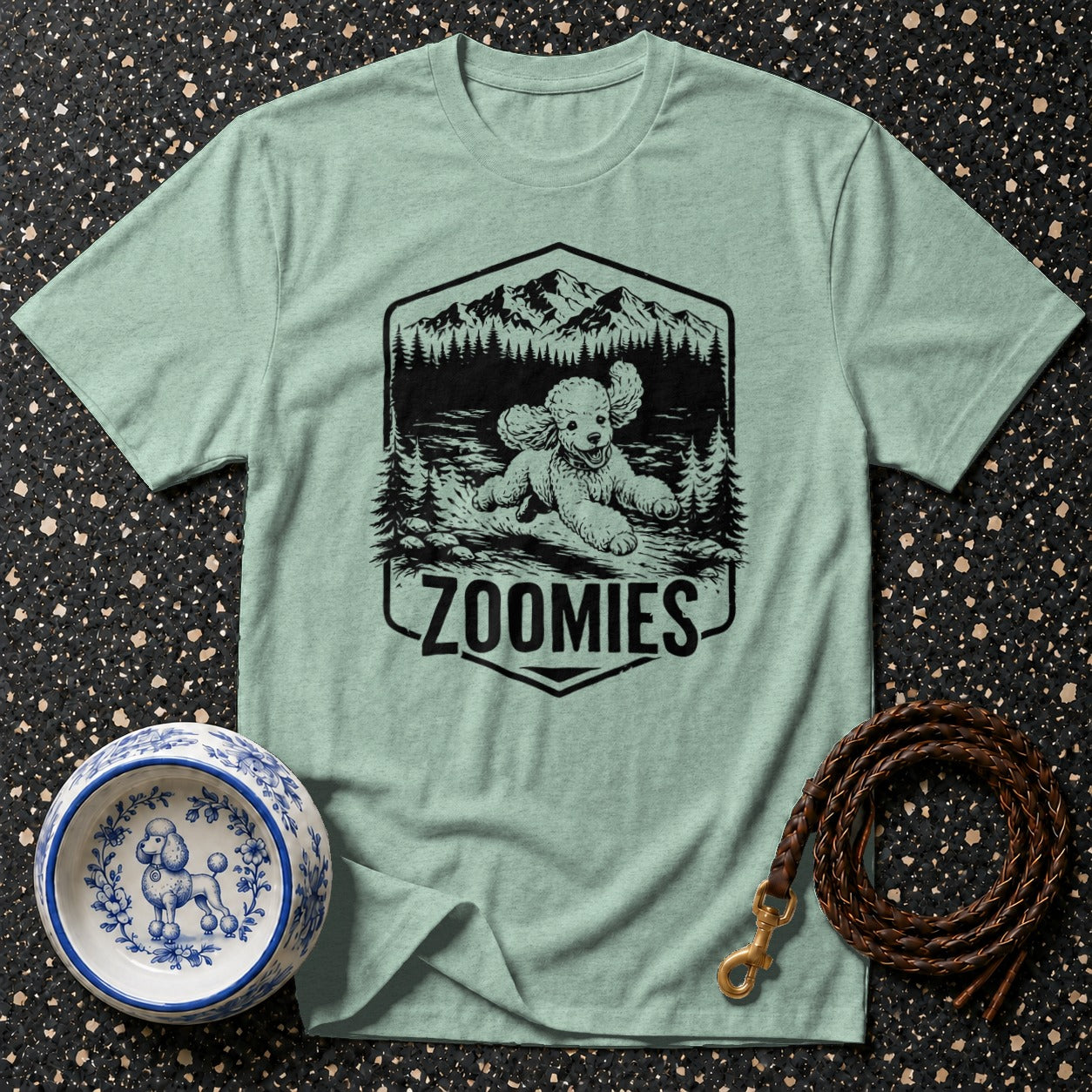 Light green t-shirt with a black graphic of a poodle in the mountains saying "Zoomies".