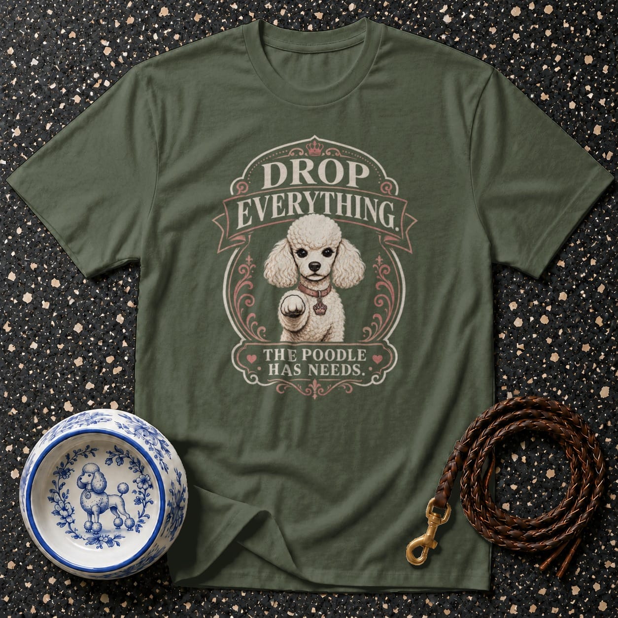 Olive green t-shirt with white poodle graphic and text "DROP EVERYTHING. THE POODLE HAS NEEDS."