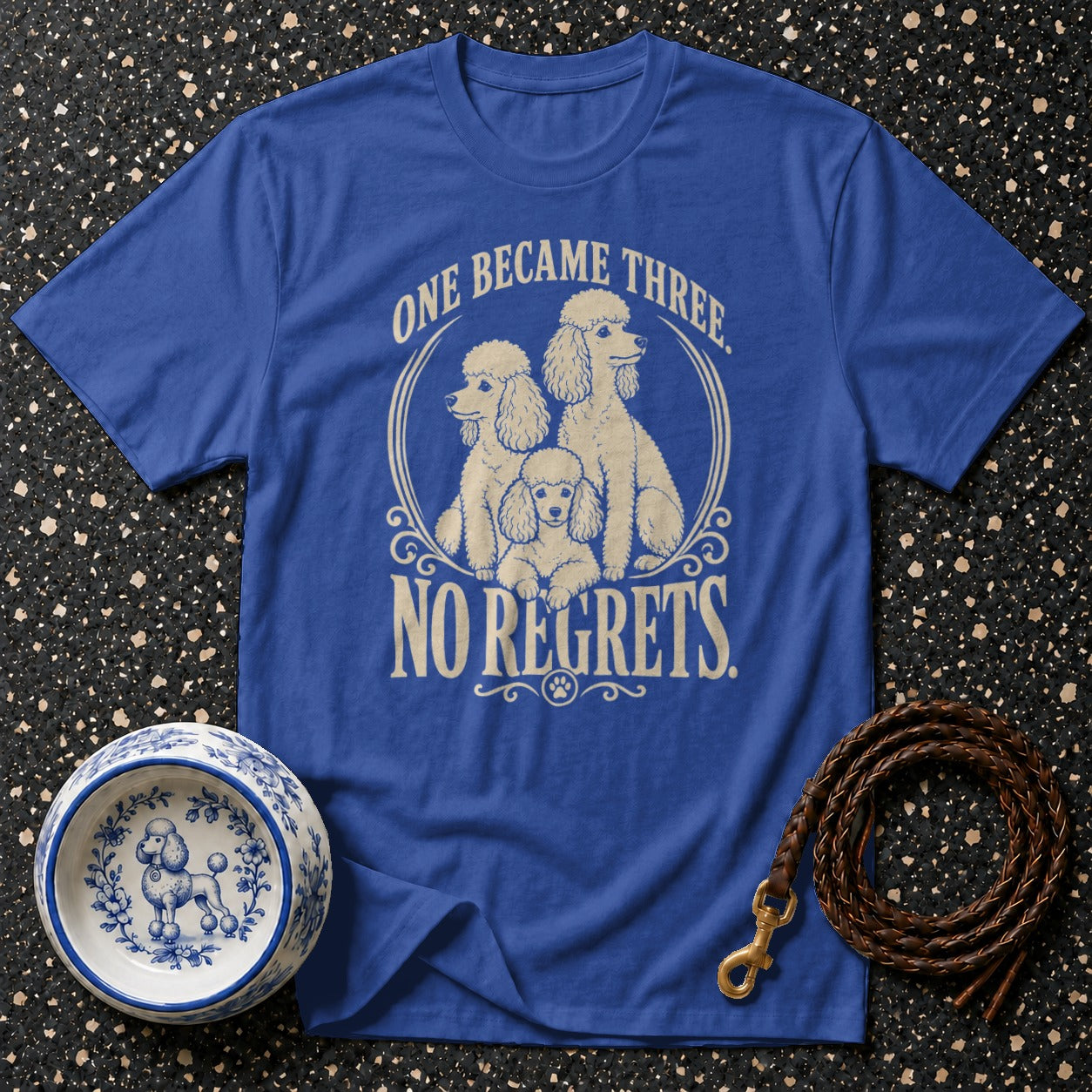 Blue t-shirt with three poodles and "One became three. No regrets." text.
