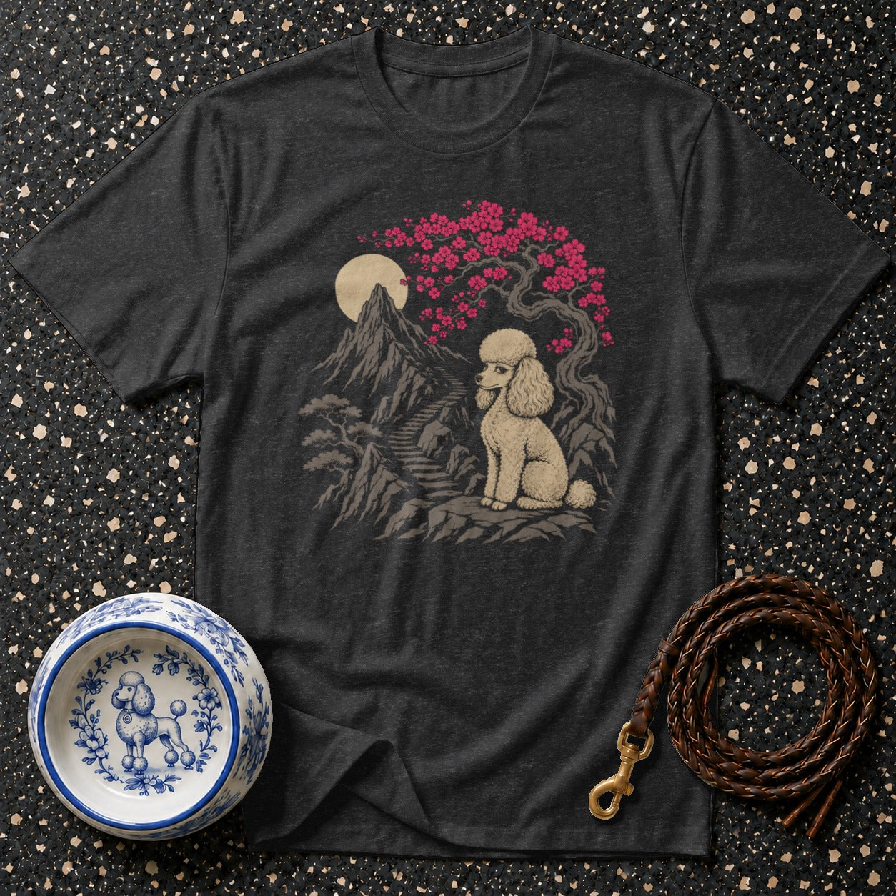 Dark grey t-shirt with a poodle sitting on rocks under a cherry blossom tree.