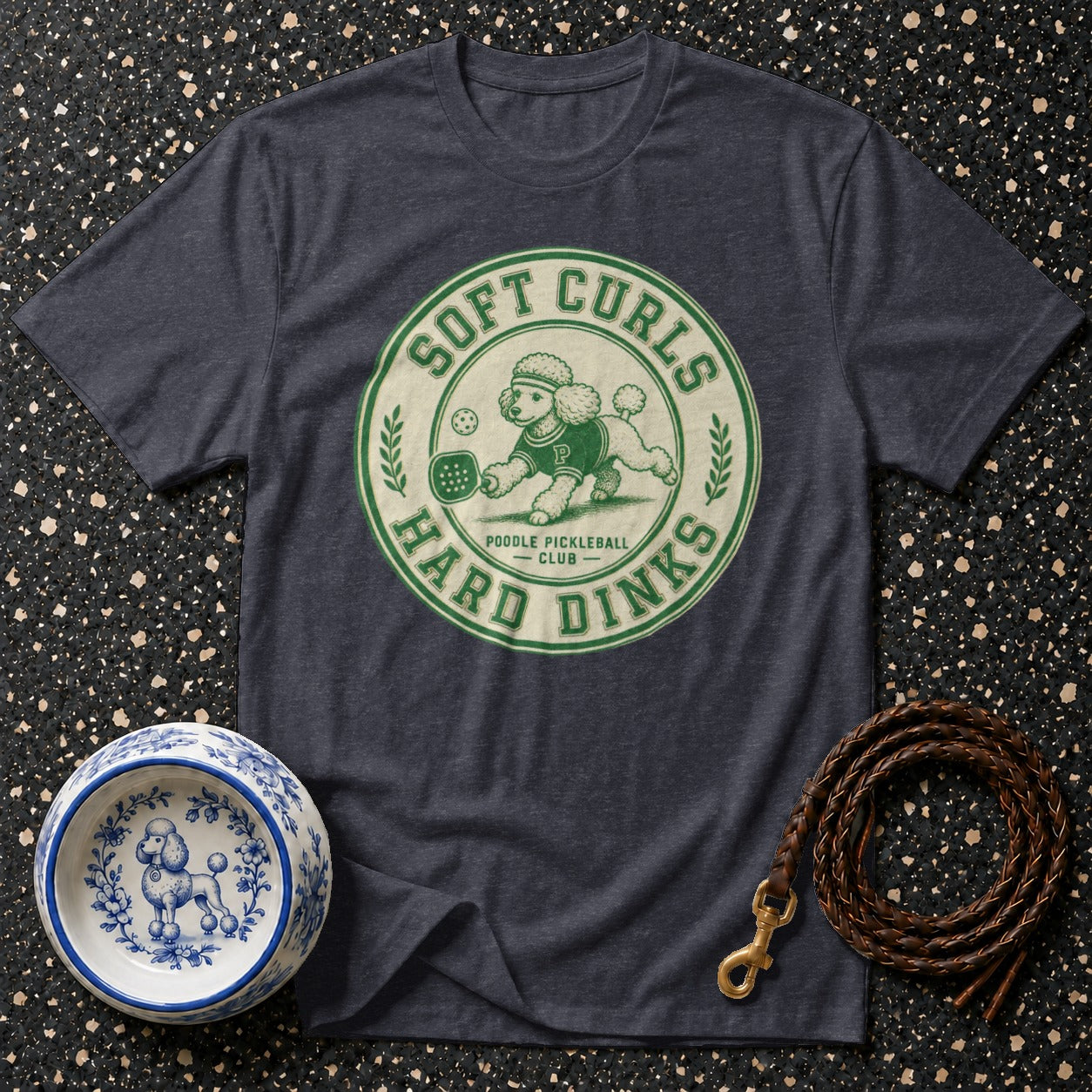 Dark t-shirt with a green circular graphic of a poodle playing pickleball, reading "Soft Curls Hard Dinks".