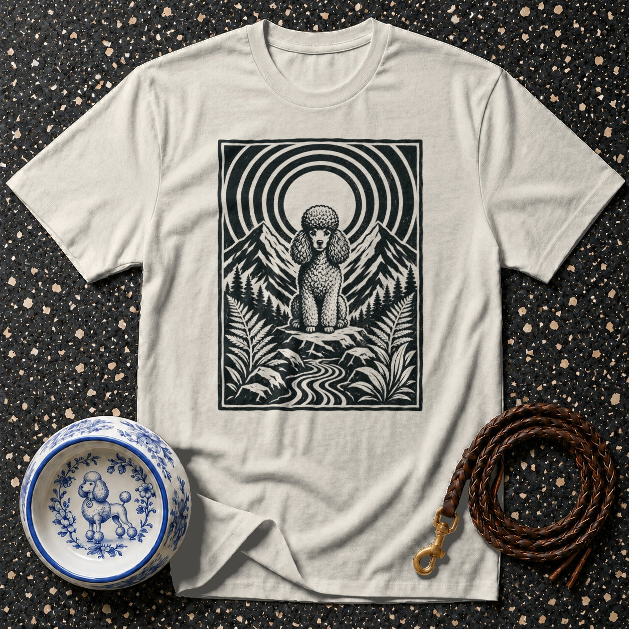 Cream t-shirt with black poodle illustration on mountain landscape.