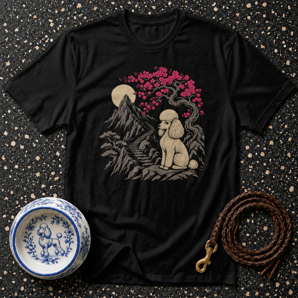 Black t-shirt with a beige poodle sitting on rocks beneath a cherry blossom tree and moon.