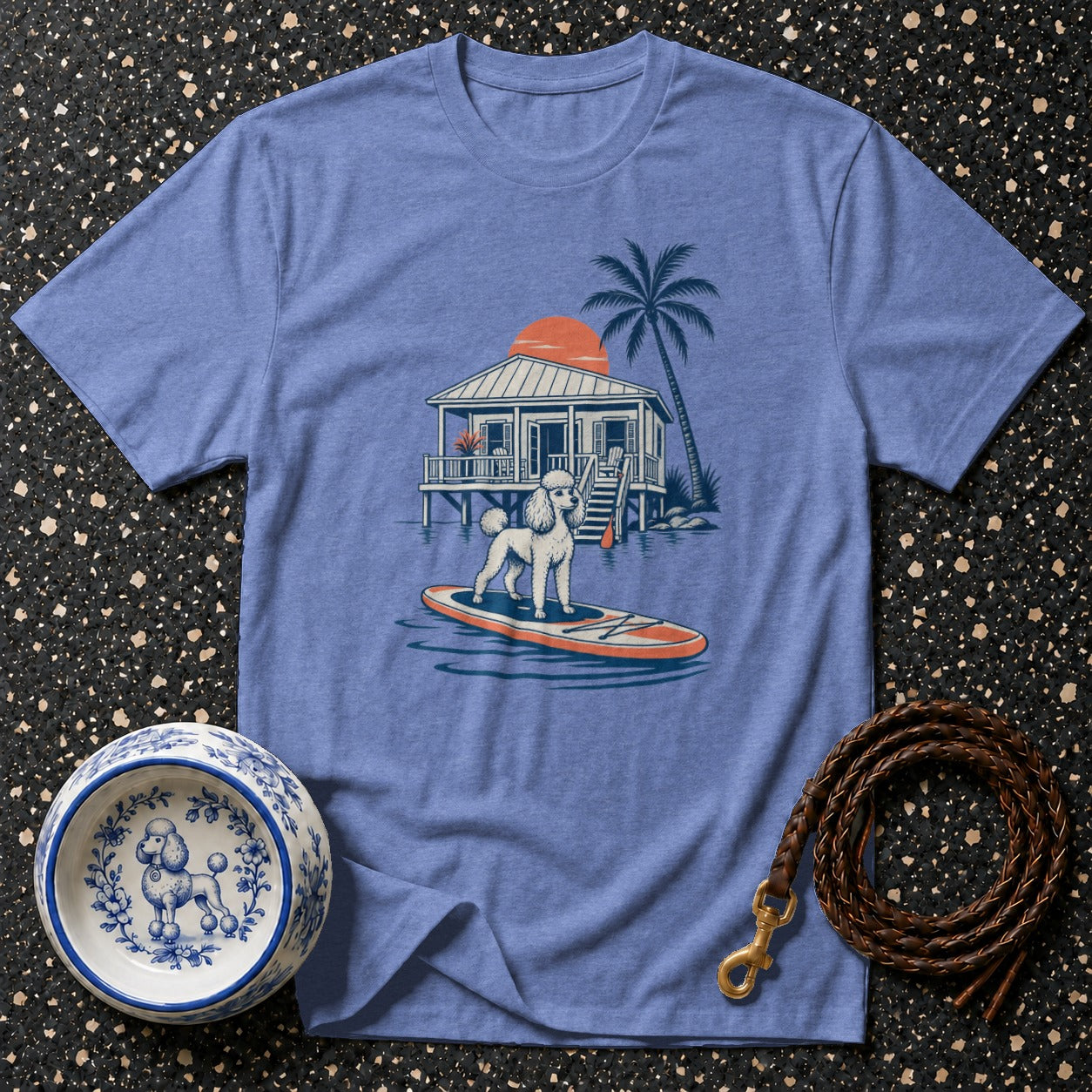 T-shirt with poodle on paddleboard, beach house, palm tree, and sun graphic.