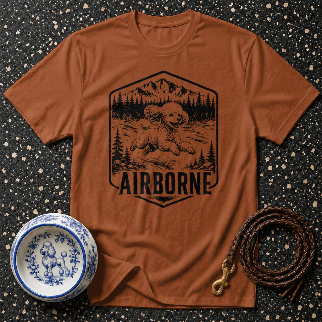 Brown t-shirt with a black graphic of a poodle in the mountains with "AIRBORNE" text.