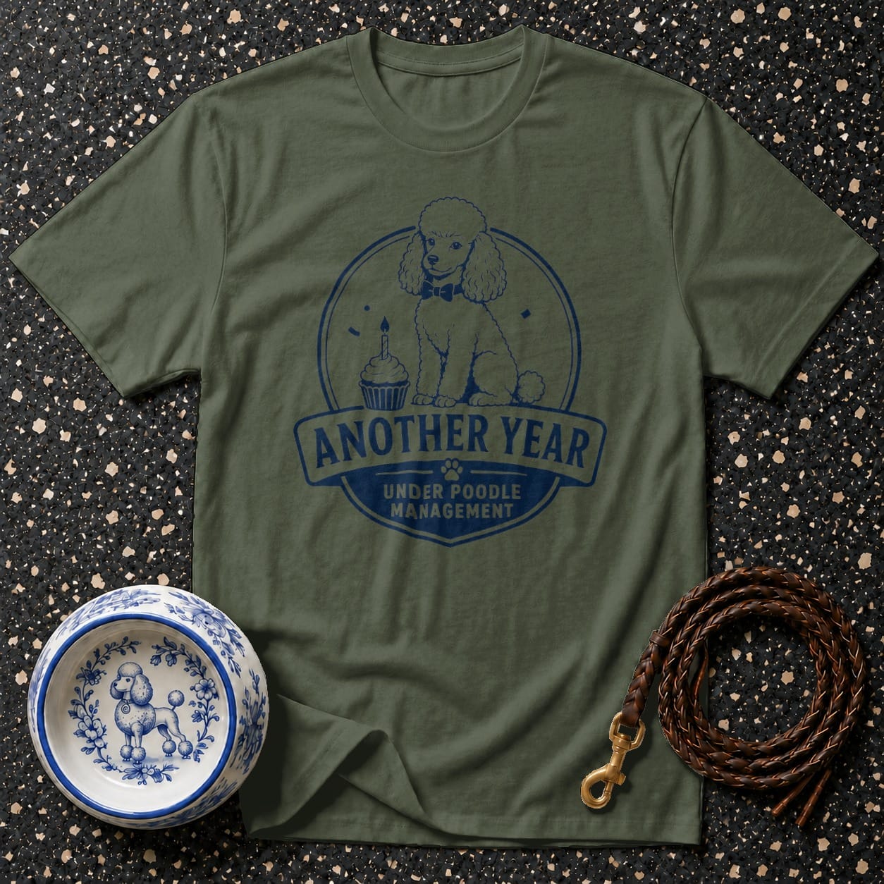 Olive green t-shirt with blue poodle graphic and text: "Another Year Under Poodle Management".