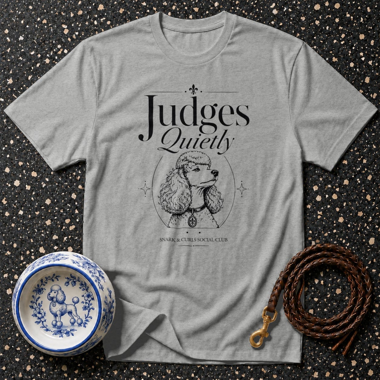 Grey t-shirt with "Judges Quietly" text and poodle illustration, with dog bowl and leash.