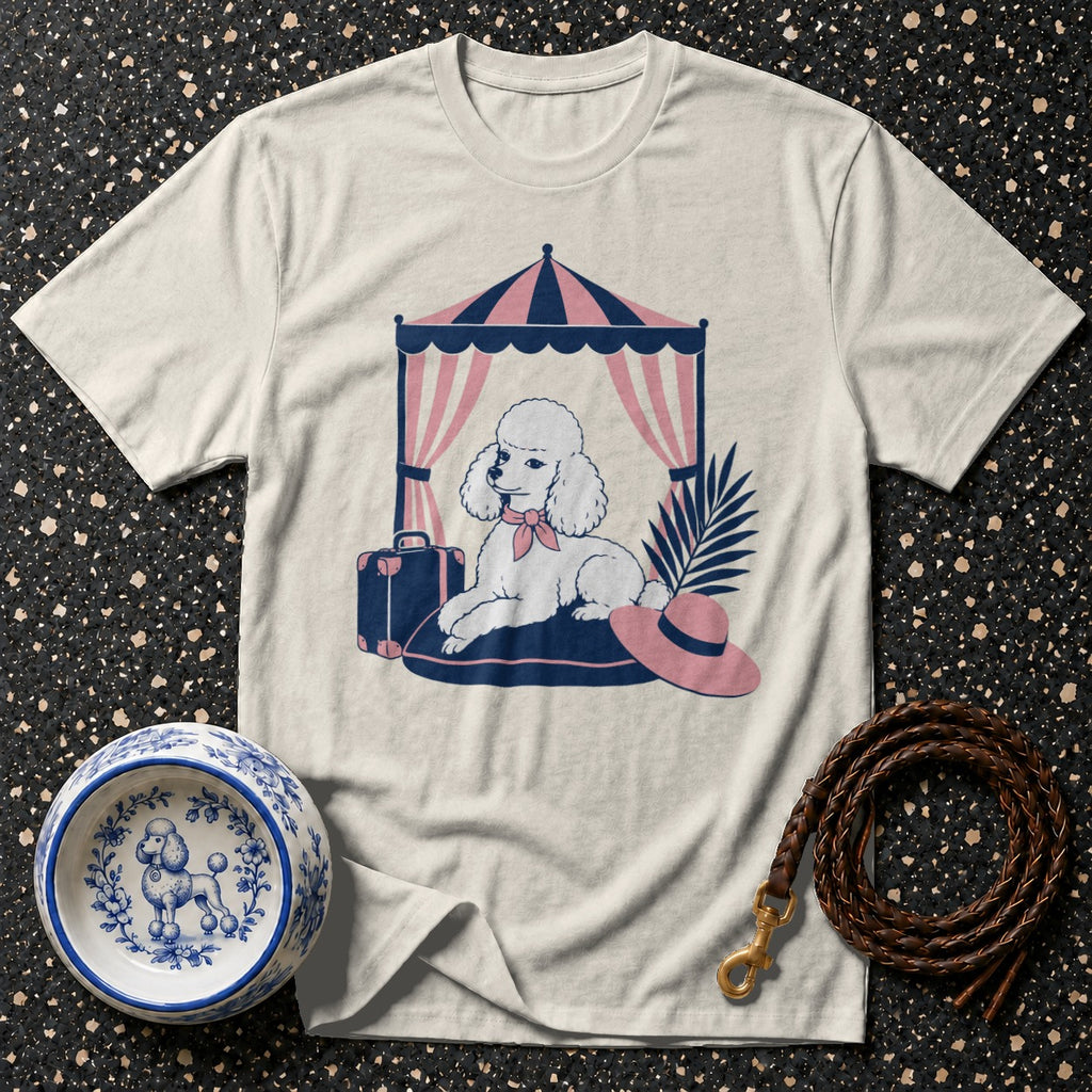 White t-shirt with a graphic of a poodle under a striped tent, next to a suitcase.