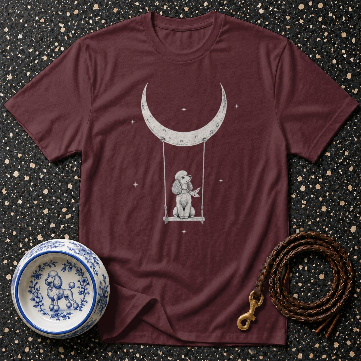 Maroon t-shirt with poodle on swing under crescent moon design.