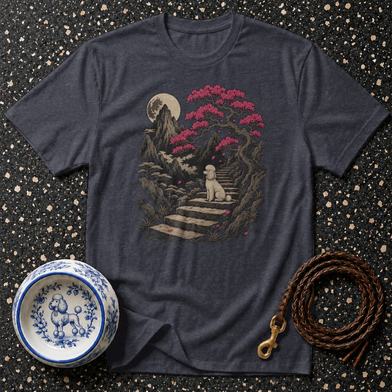 Dark t-shirt features a poodle on a stone staircase under a cherry blossom tree and moon.