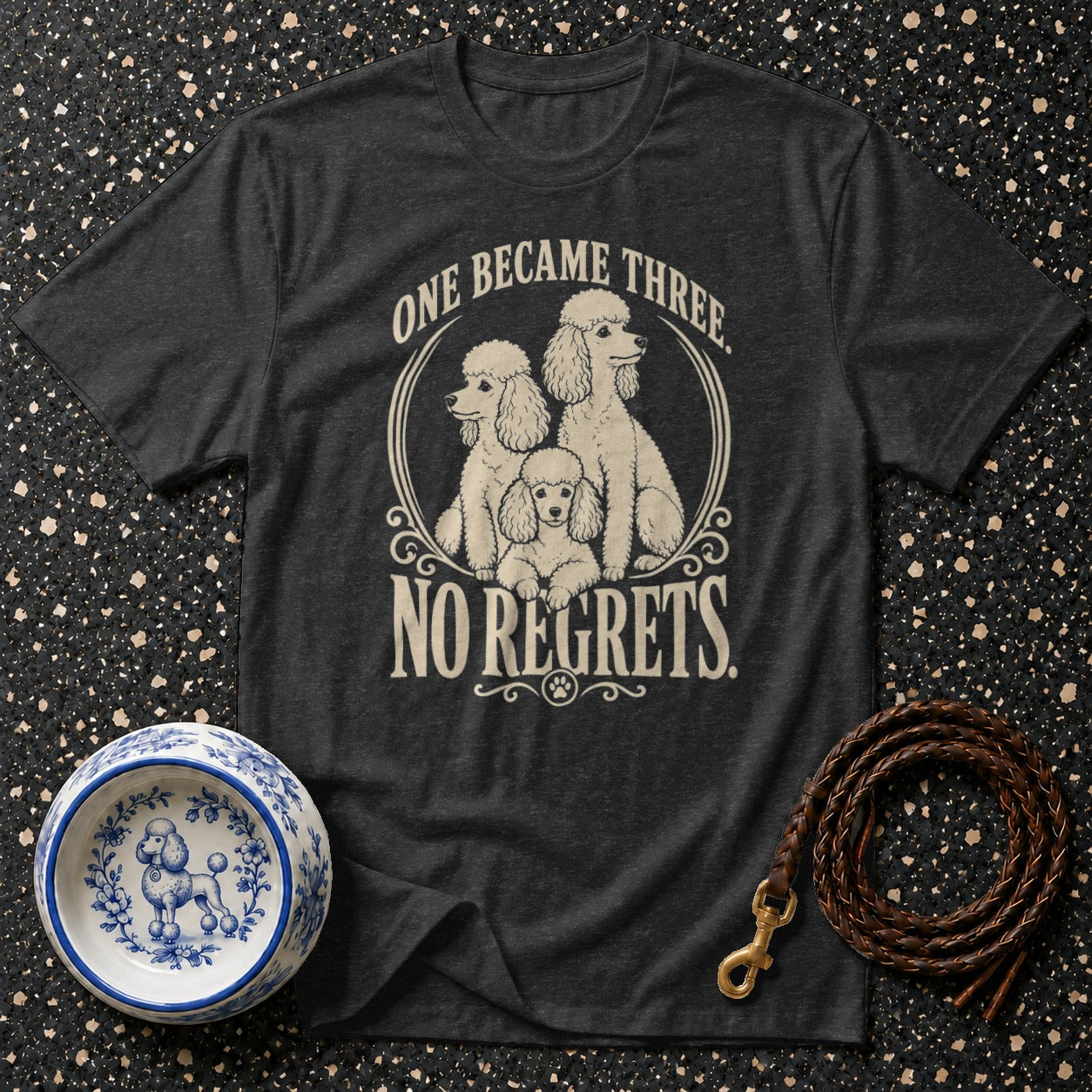 Dark t-shirt with cream graphic of three poodles and text "ONE BECAME THREE. NO REGRETS."
