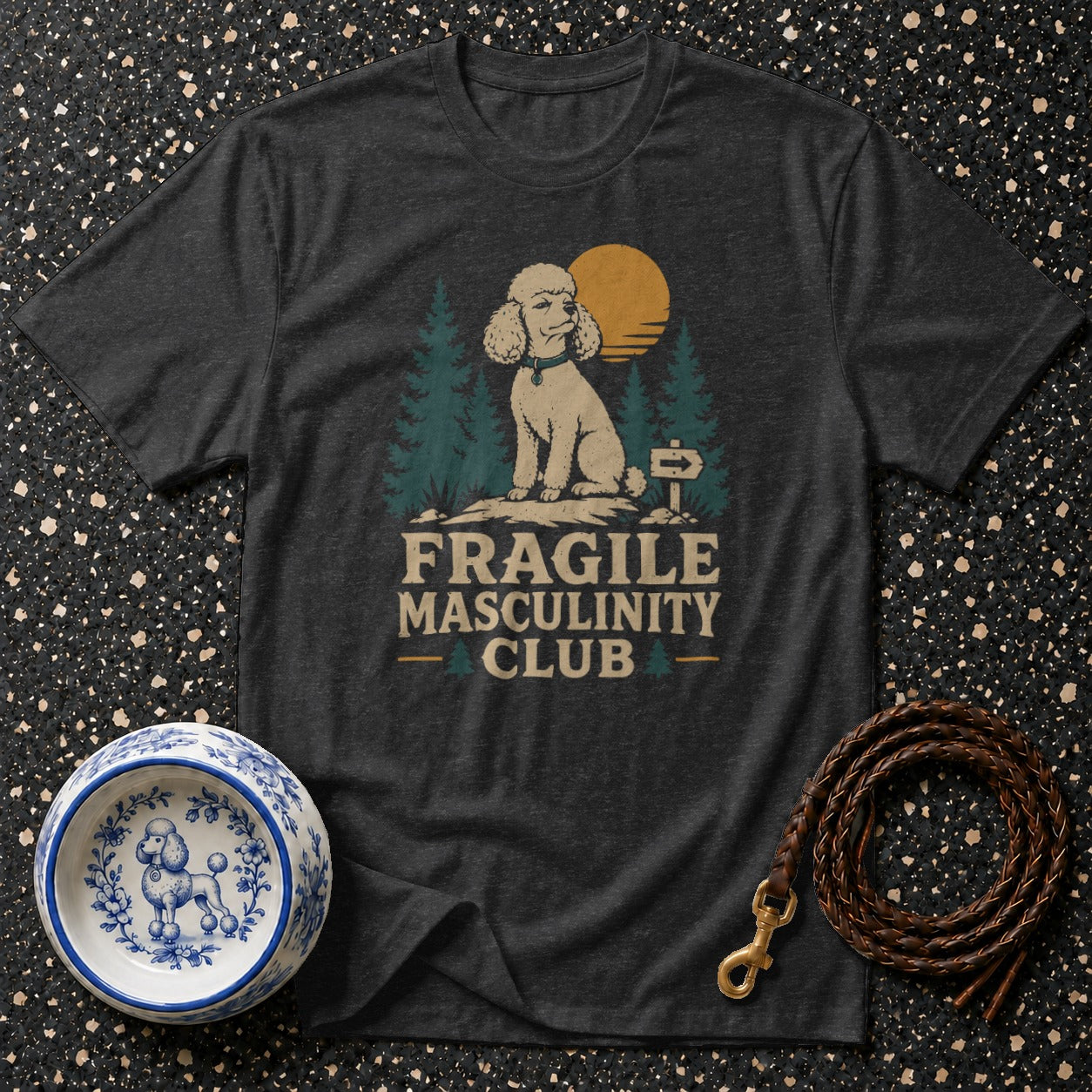 Dark t-shirt with a graphic of a poodle in a forest setting with the text "FRAGILE MASCULINITY CLUB".