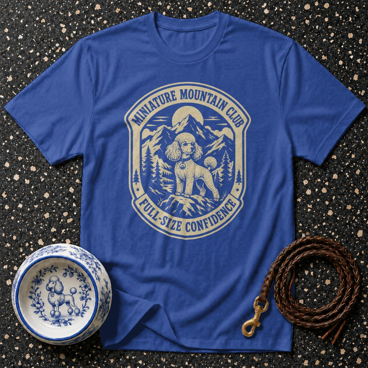 Blue t-shirt with a crest featuring a poodle and mountains, reading "Miniature Mountain Club" and "Full-Size Confidence."