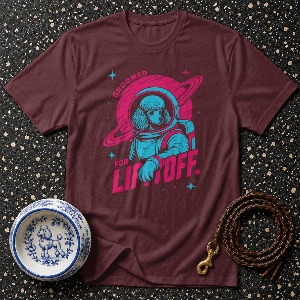 Maroon t-shirt with poodle astronaut graphic and text "Groomed for Liftoff".