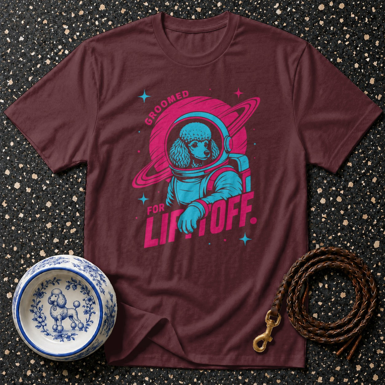 Maroon t-shirt with poodle astronaut graphic and text "Groomed for Liftoff".