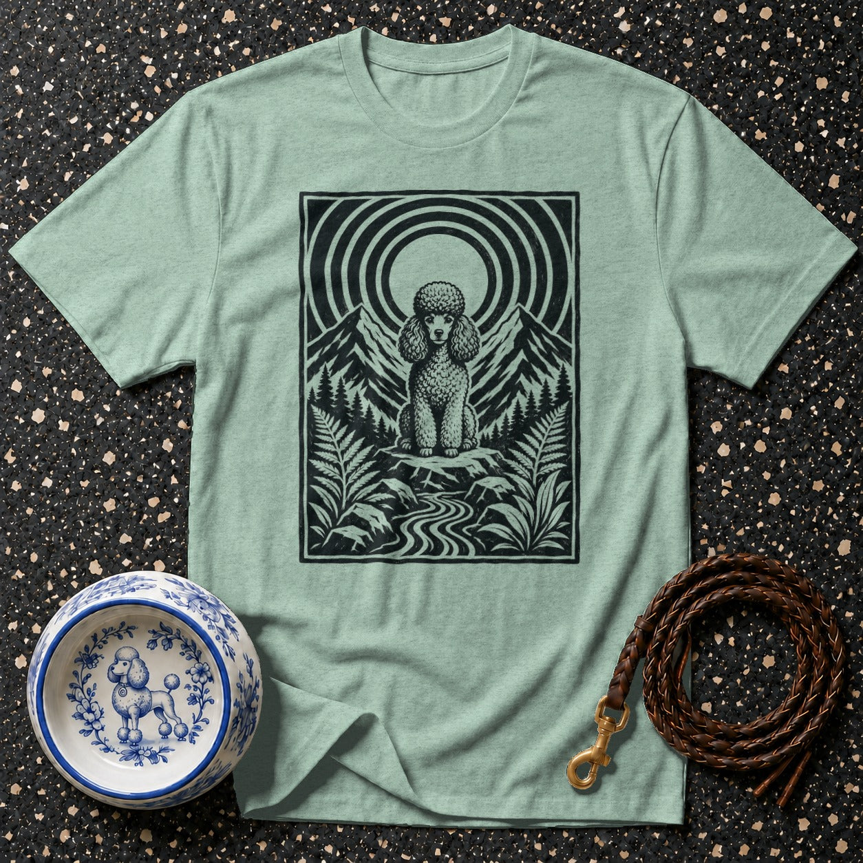 Green t-shirt with black graphic of a poodle in a mountainous landscape.