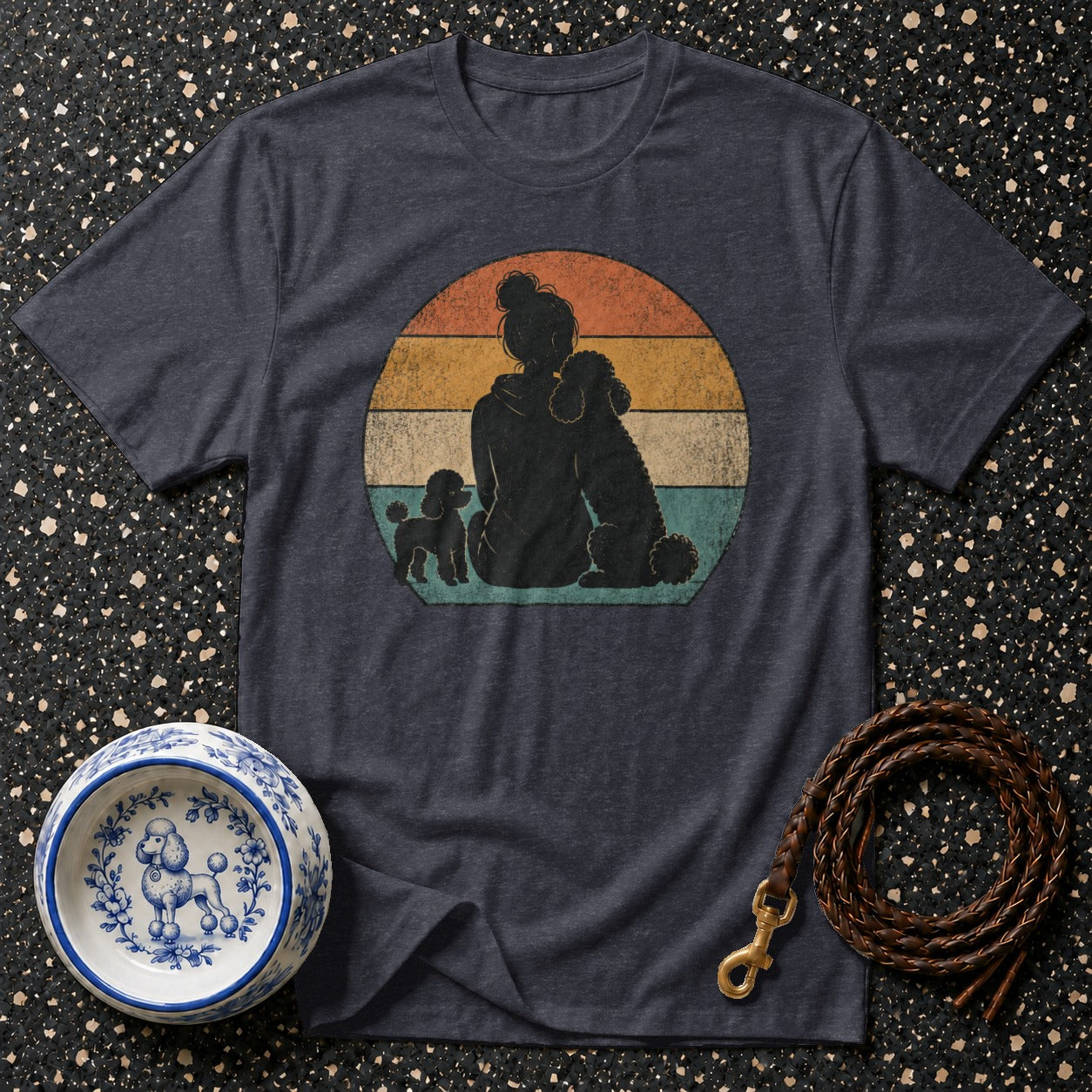 Dark t-shirt with graphic of person and poodles against striped sunset circle.