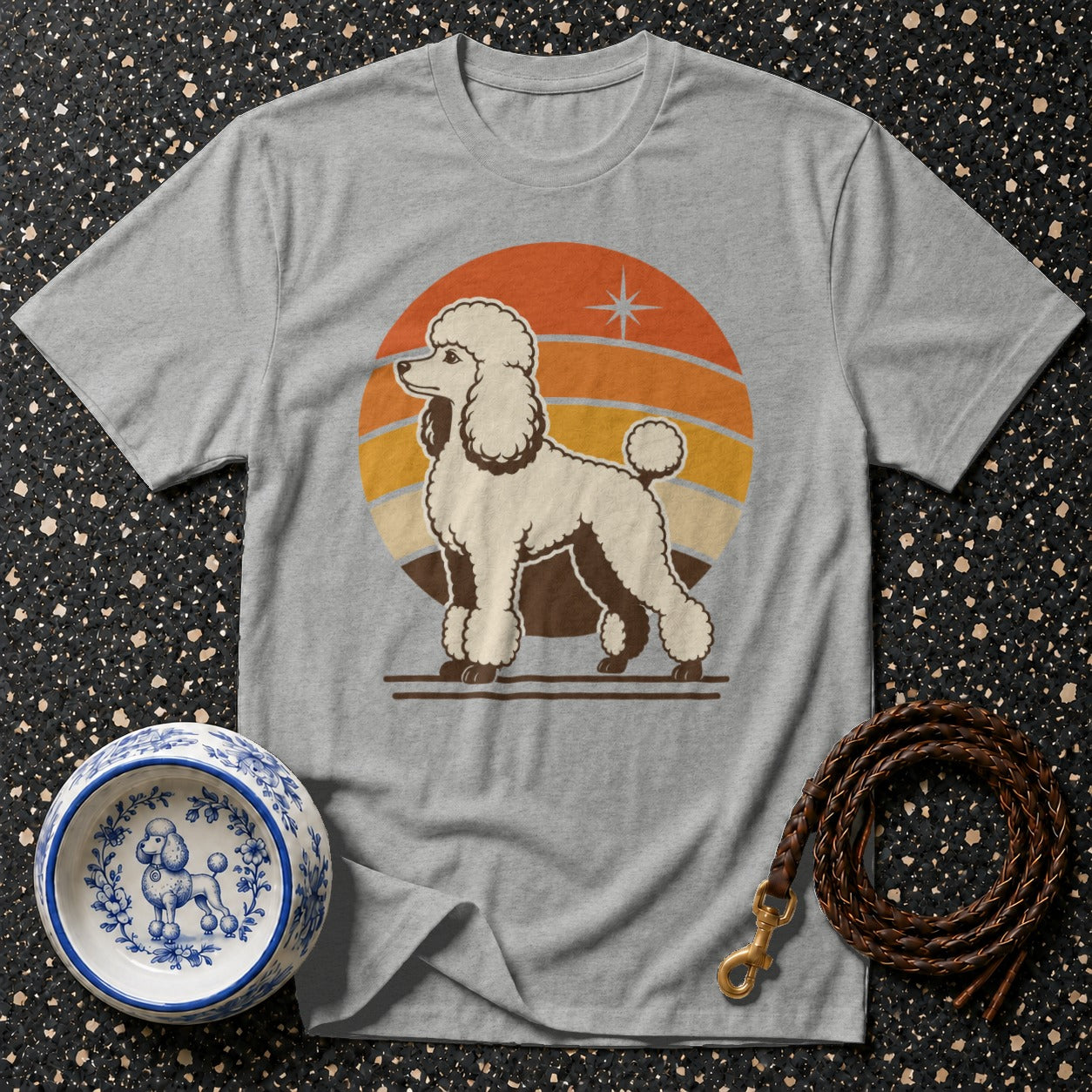 Grey t-shirt with a white poodle graphic in front of a retro sunset.