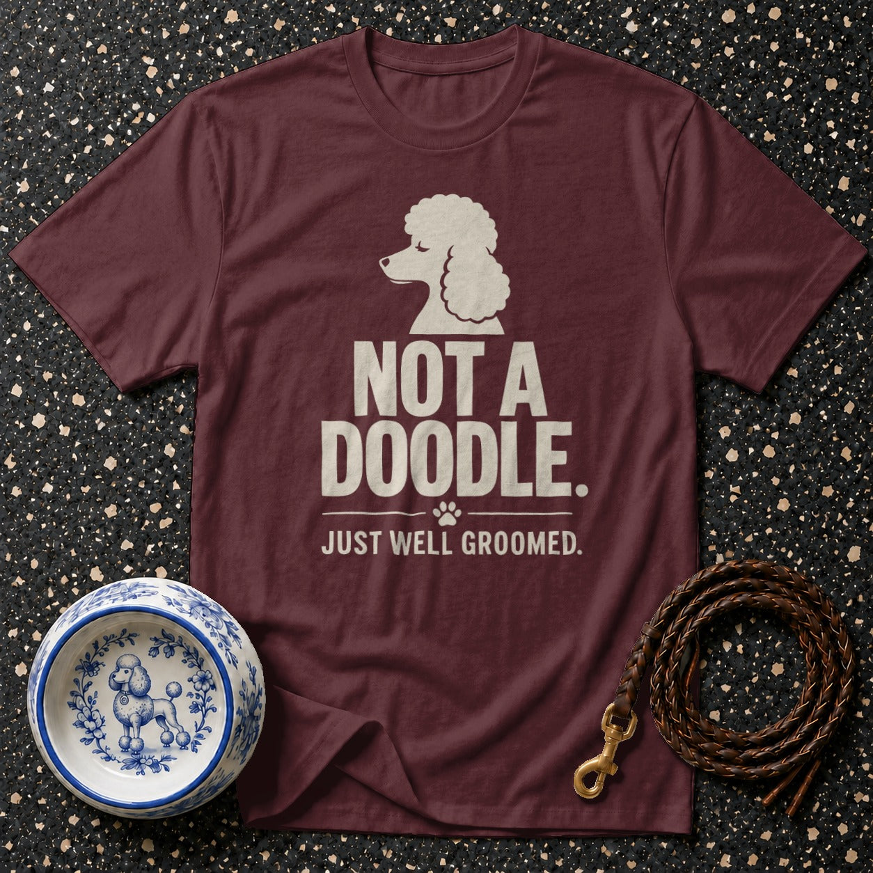 Maroon t-shirt with a white poodle graphic and "NOT A DOODLE. JUST WELL GROOMED." text.