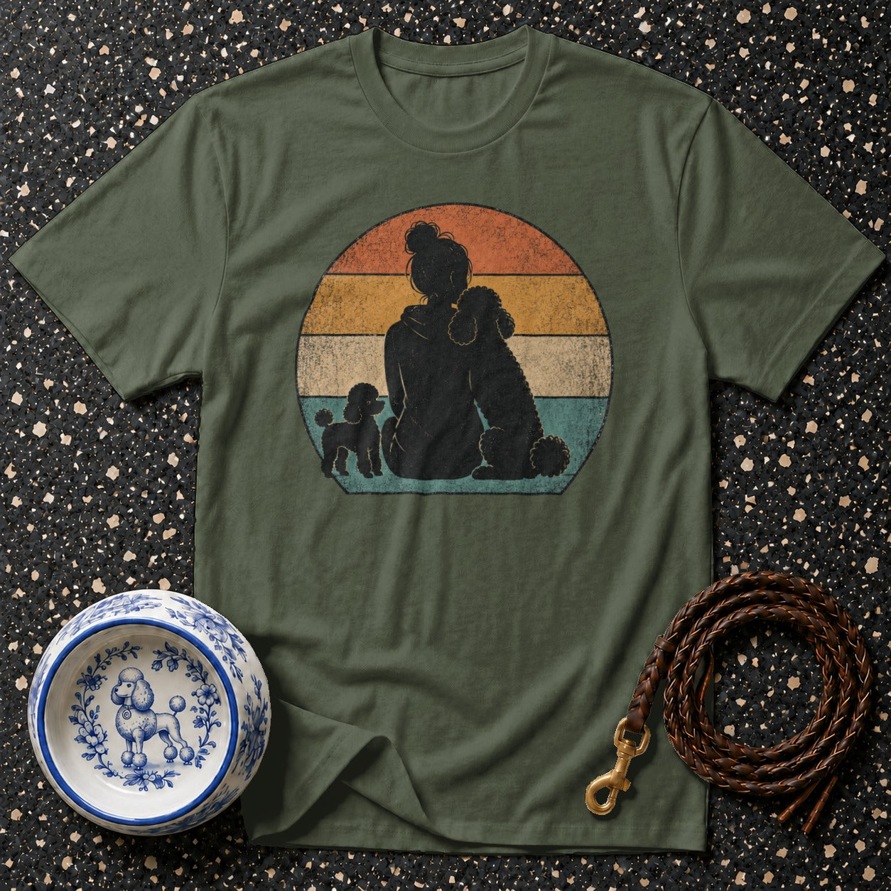Olive t-shirt with silhouette of person and two poodles against vintage sunset background.