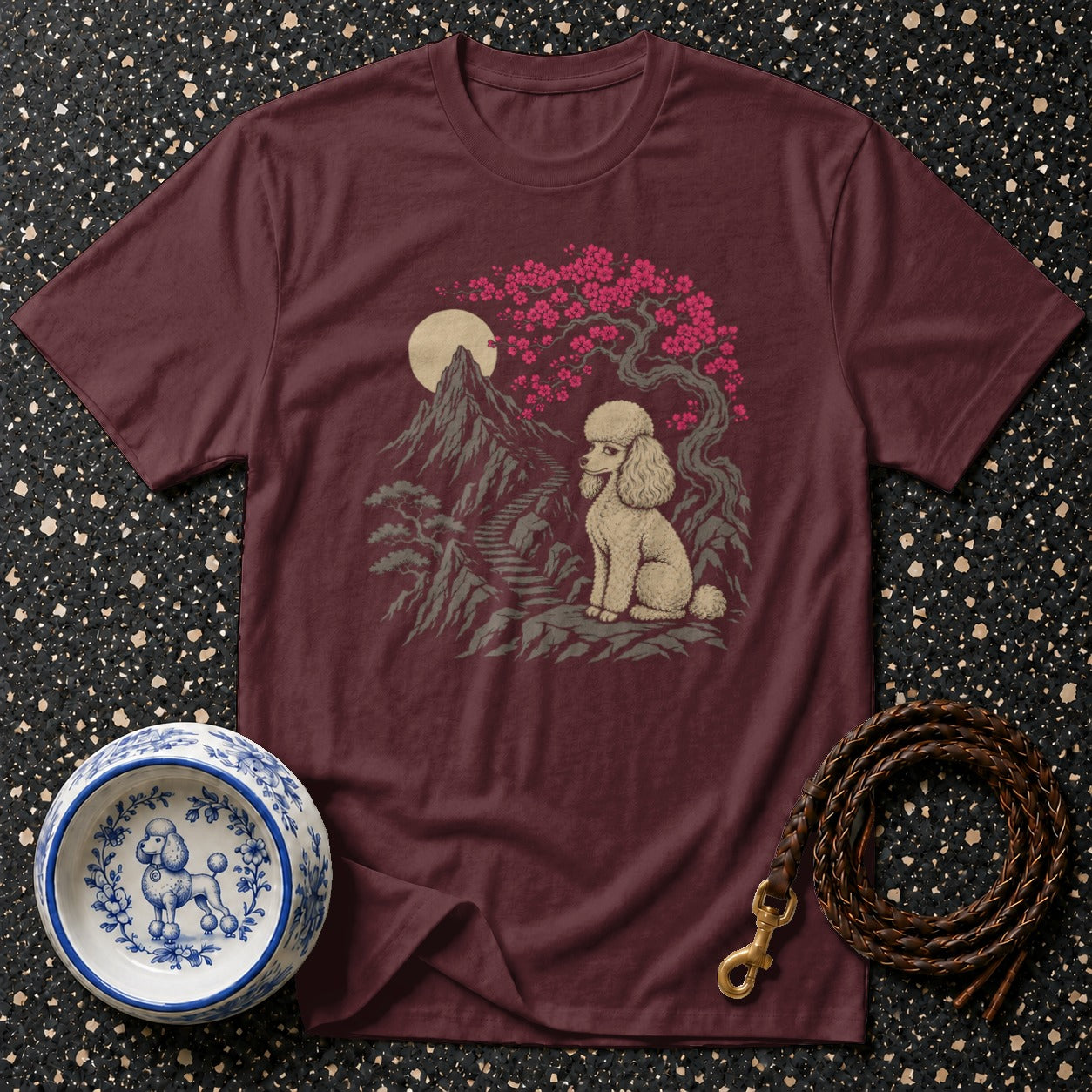 Maroon t-shirt featuring a cream poodle sitting by a cherry blossom tree and mountains.