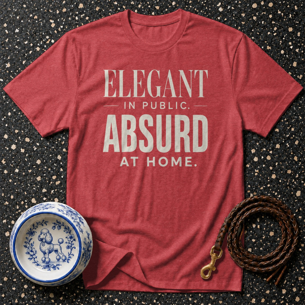 Red t-shirt with text "ELEGANT IN PUBLIC. ABSURD AT HOME."