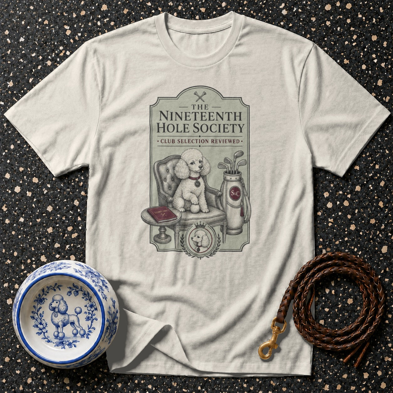 T-shirt graphic: Poodle with golf clubs and text "The Nineteenth Hole Society".