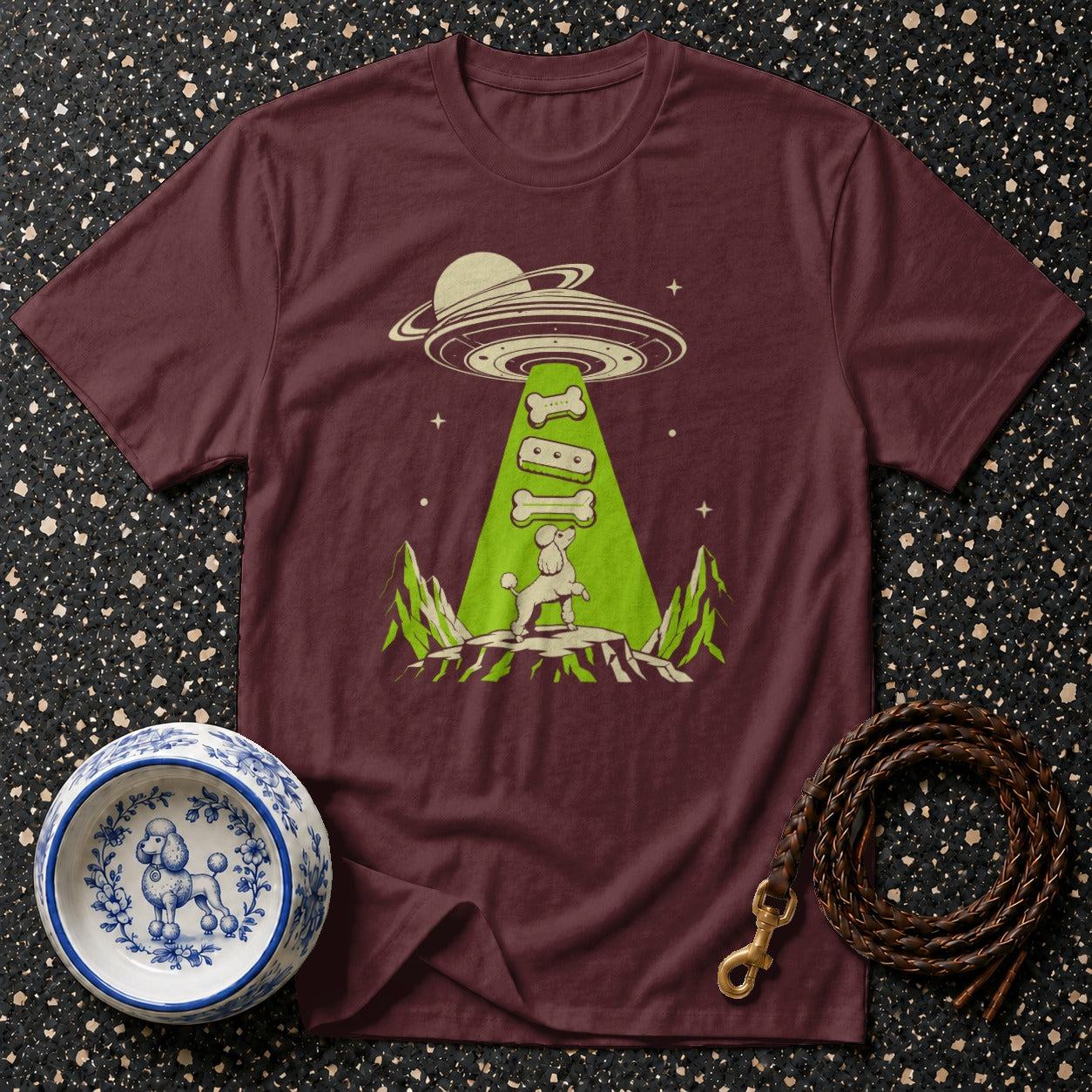 Maroon t-shirt with a poodle being beamed up by a UFO, holding dog bones.