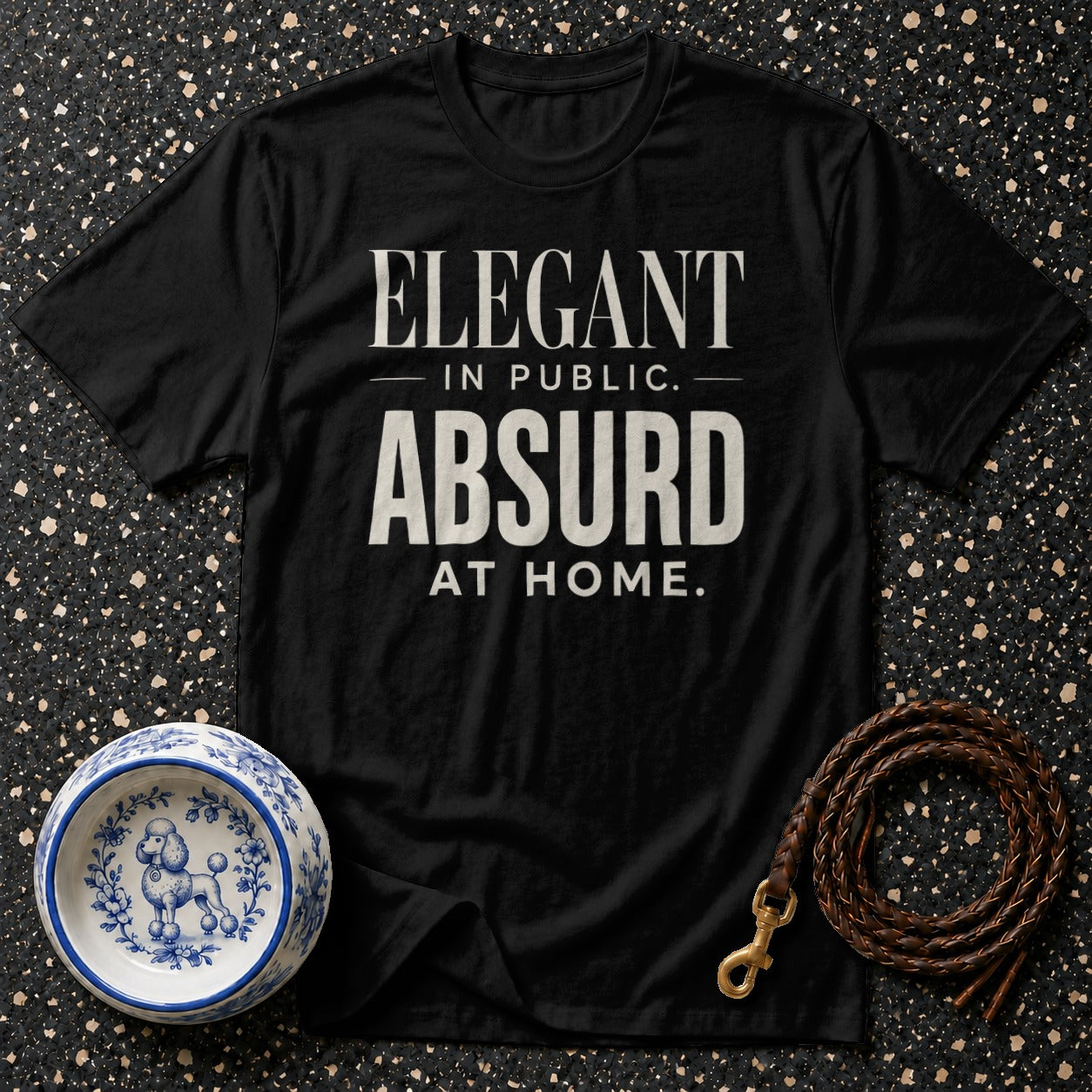 Black t-shirt with "ELEGANT IN PUBLIC. ABSURD AT HOME." text.