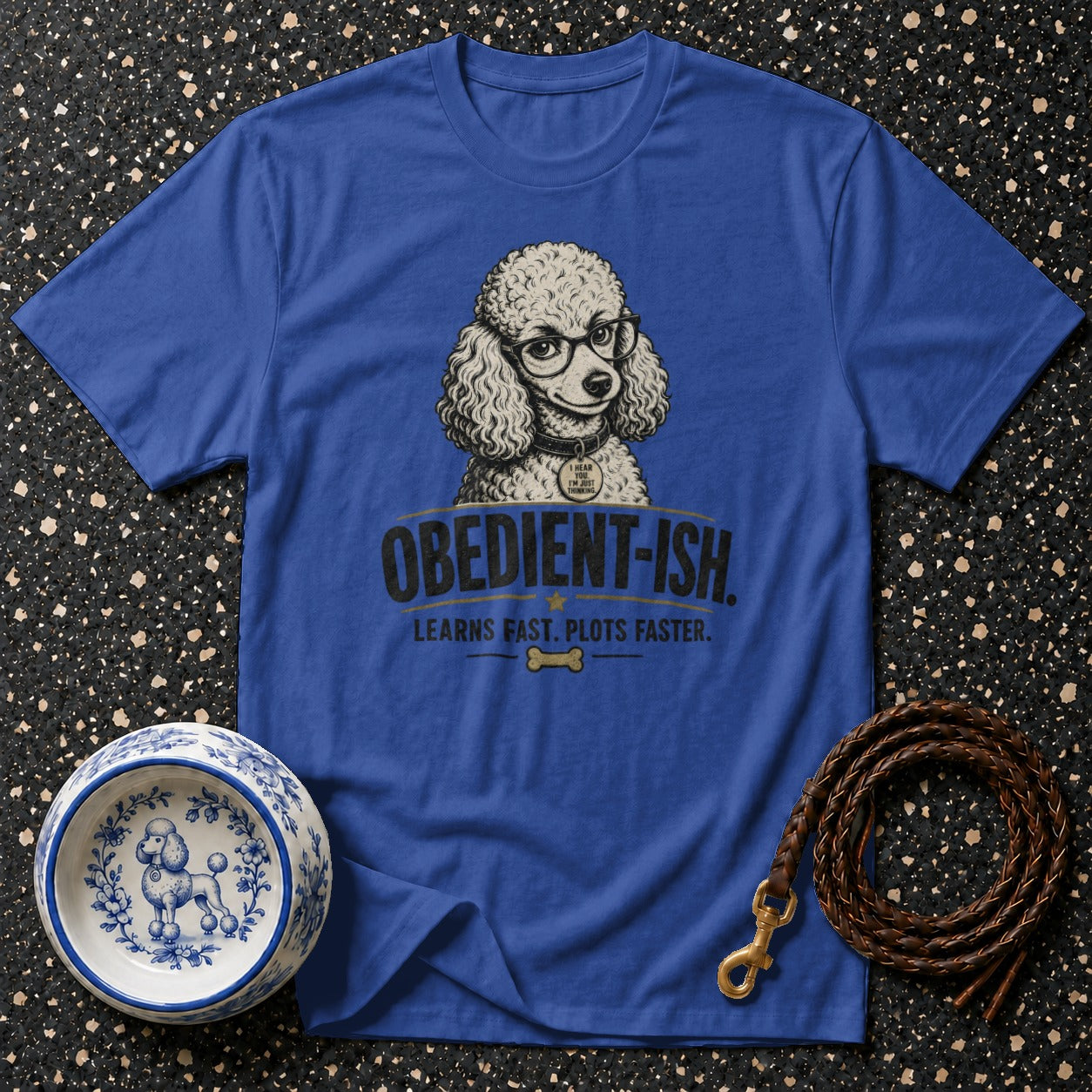 Blue t-shirt with a poodle wearing glasses titled "Obedient-ish. Learns fast. Plots faster."