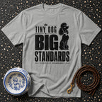 Grey t-shirt with black text and poodle graphic: "Tiny Dog Big Standards Please Act Accordingly."