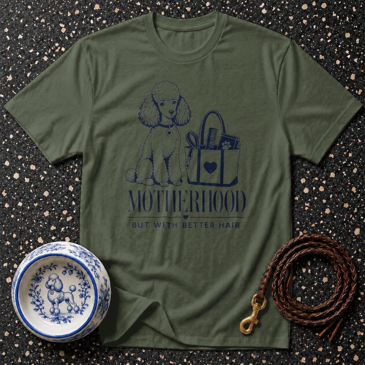 Green t-shirt with a poodle, grooming bag, and text: Motherhood but with better hair.