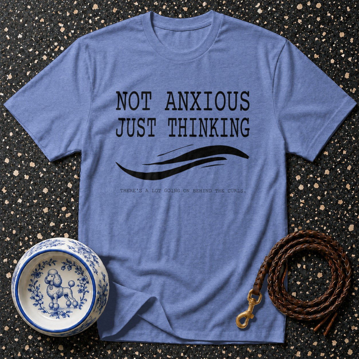 Blue t-shirt with black text "NOT ANXIOUS JUST THINKING", wavy lines, and small text "THERE'S A LOT GOING ON BEHIND THE CURLS."