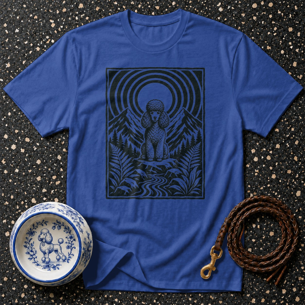 Blue t-shirt with black poodle graphic in a mountain scene.
