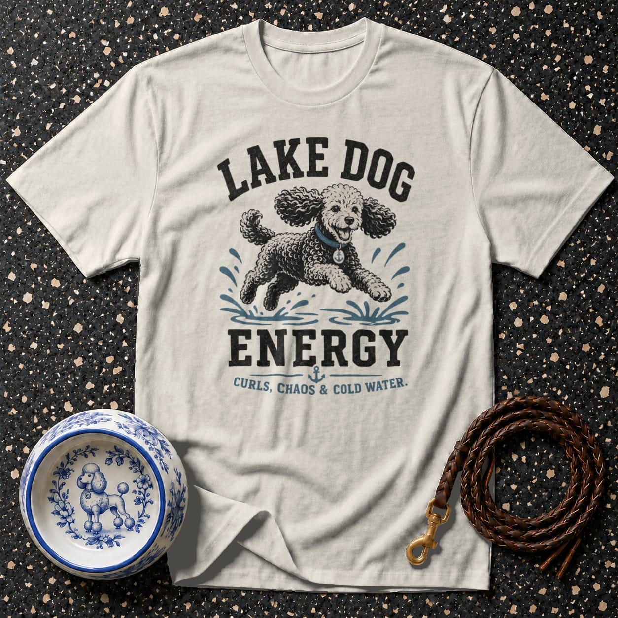 T-shirt with "Lake Dog Energy" and poodle graphic, beside a poodle-design bowl and leash.