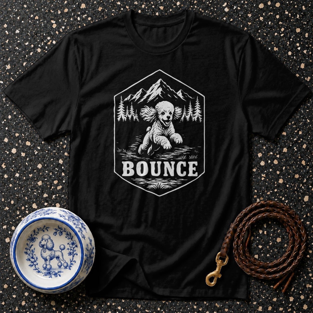 Black t-shirt with a graphic of a poodle running in nature under text "BOUNCE".