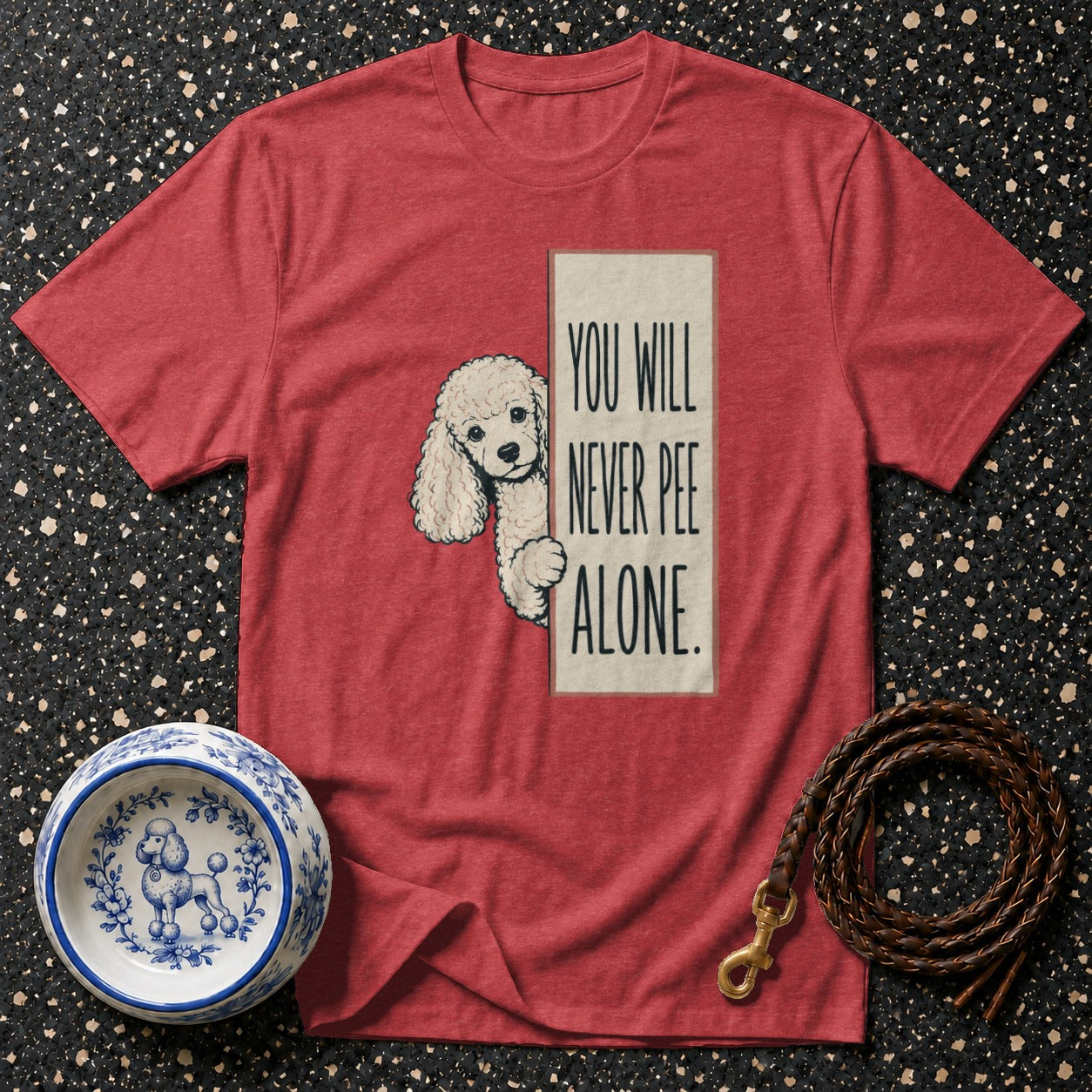 Red t-shirt with a poodle peeking from behind text reading "YOU WILL NEVER PEE ALONE".