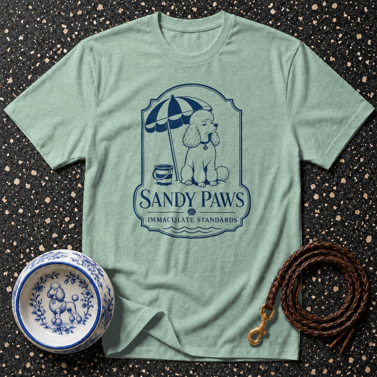 Light green t-shirt featuring a navy blue graphic of a poodle with "Sandy Paws" text.