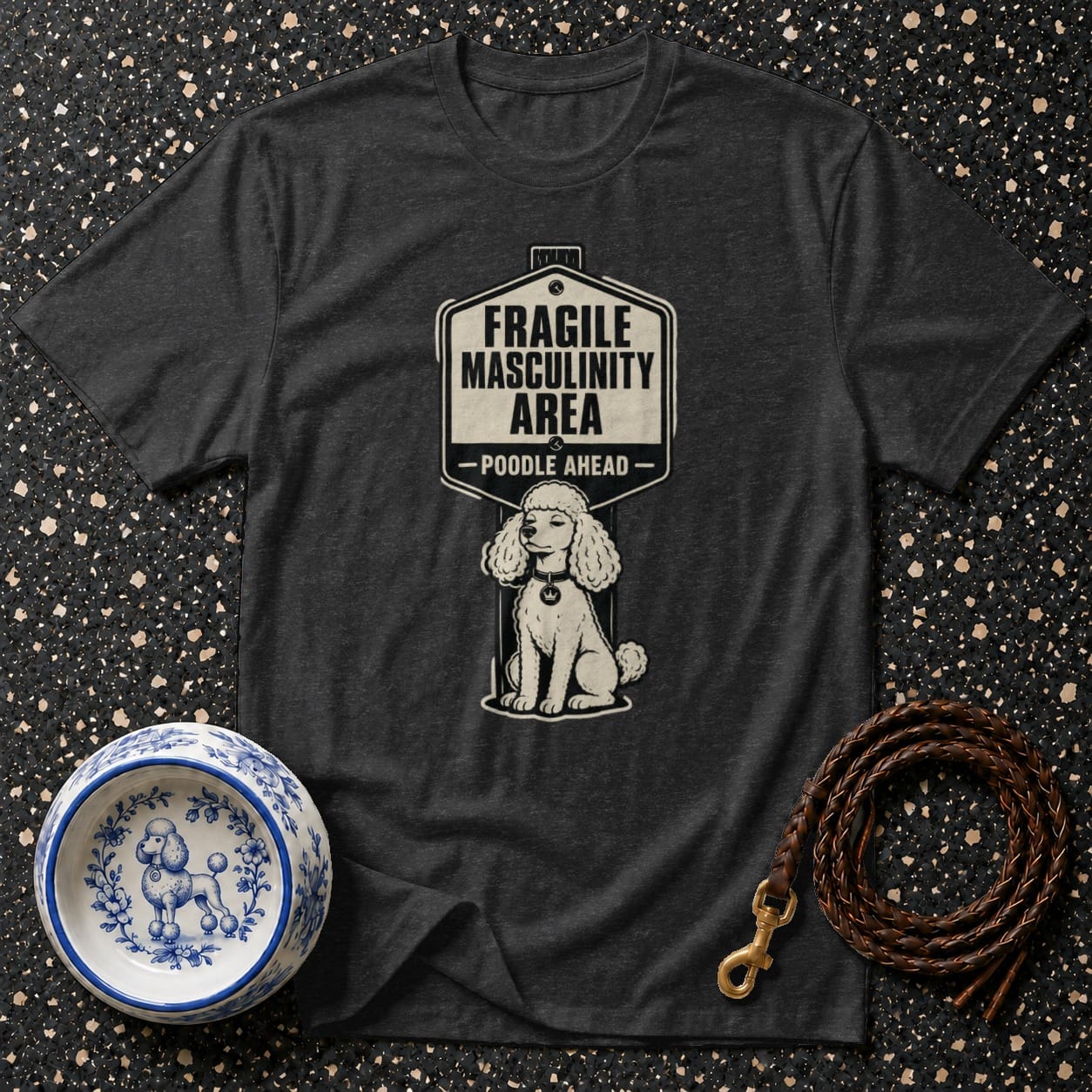 Dark t-shirt with a sign graphic reading "FRAGILE MASCULINITY AREA - POODLE AHEAD" and a poodle illustration.
