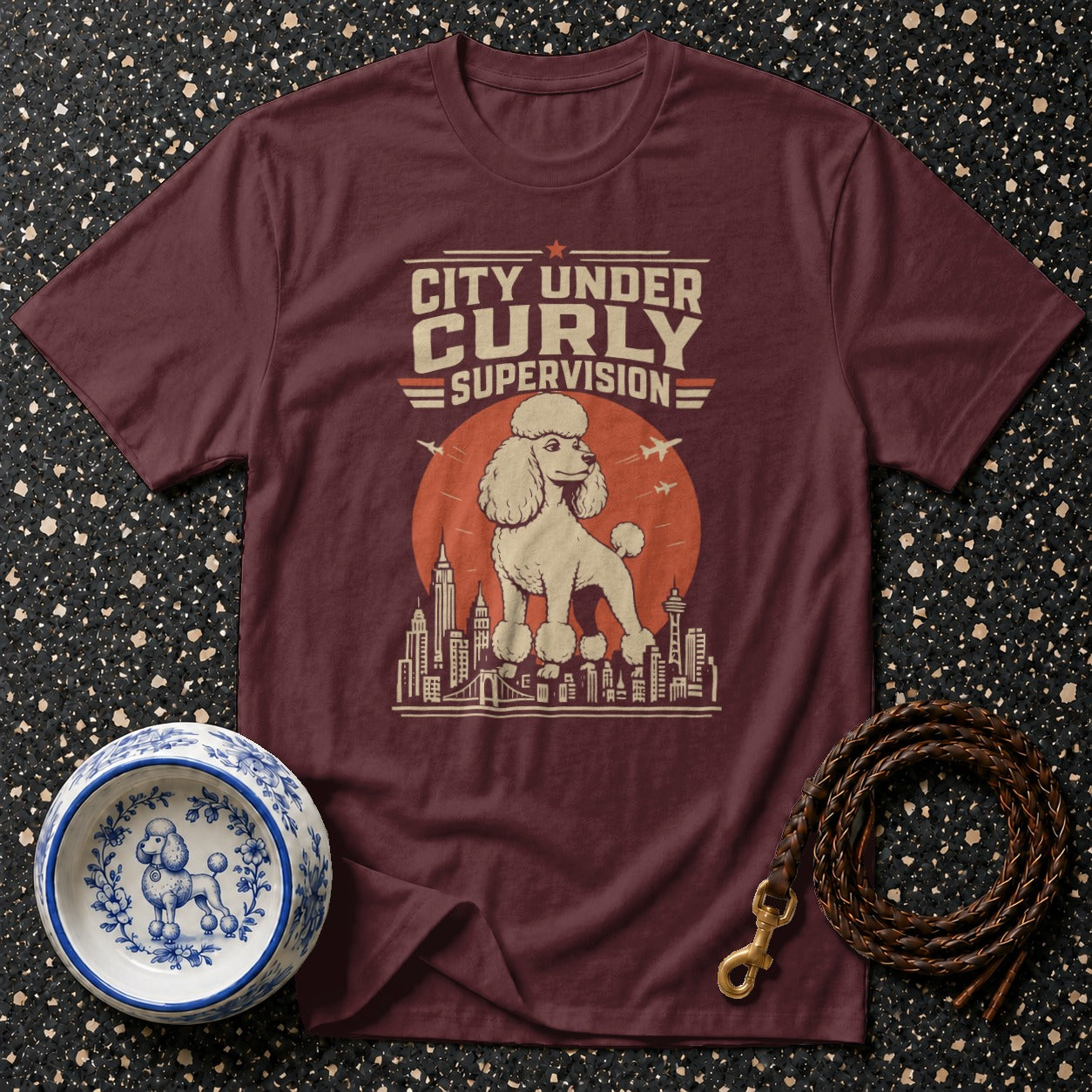 Maroon t-shirt with "City Under Curly Supervision" text and a poodle on a cityscape.