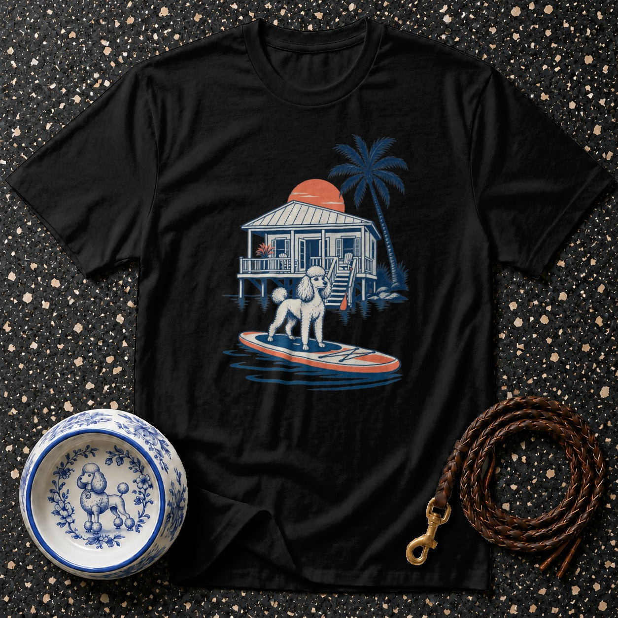 Black t-shirt with graphic of poodle on paddleboard by beach house.