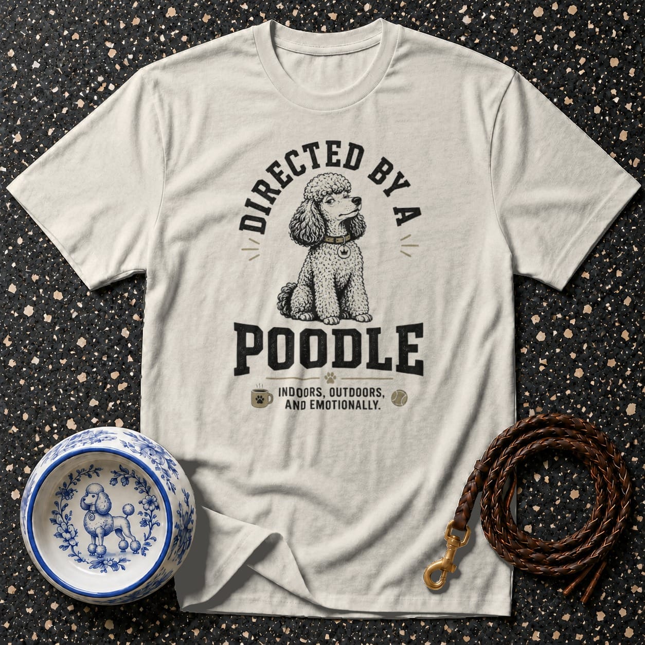 Cream t-shirt with "Directed by a Poodle" graphic and dog bowl and leash.