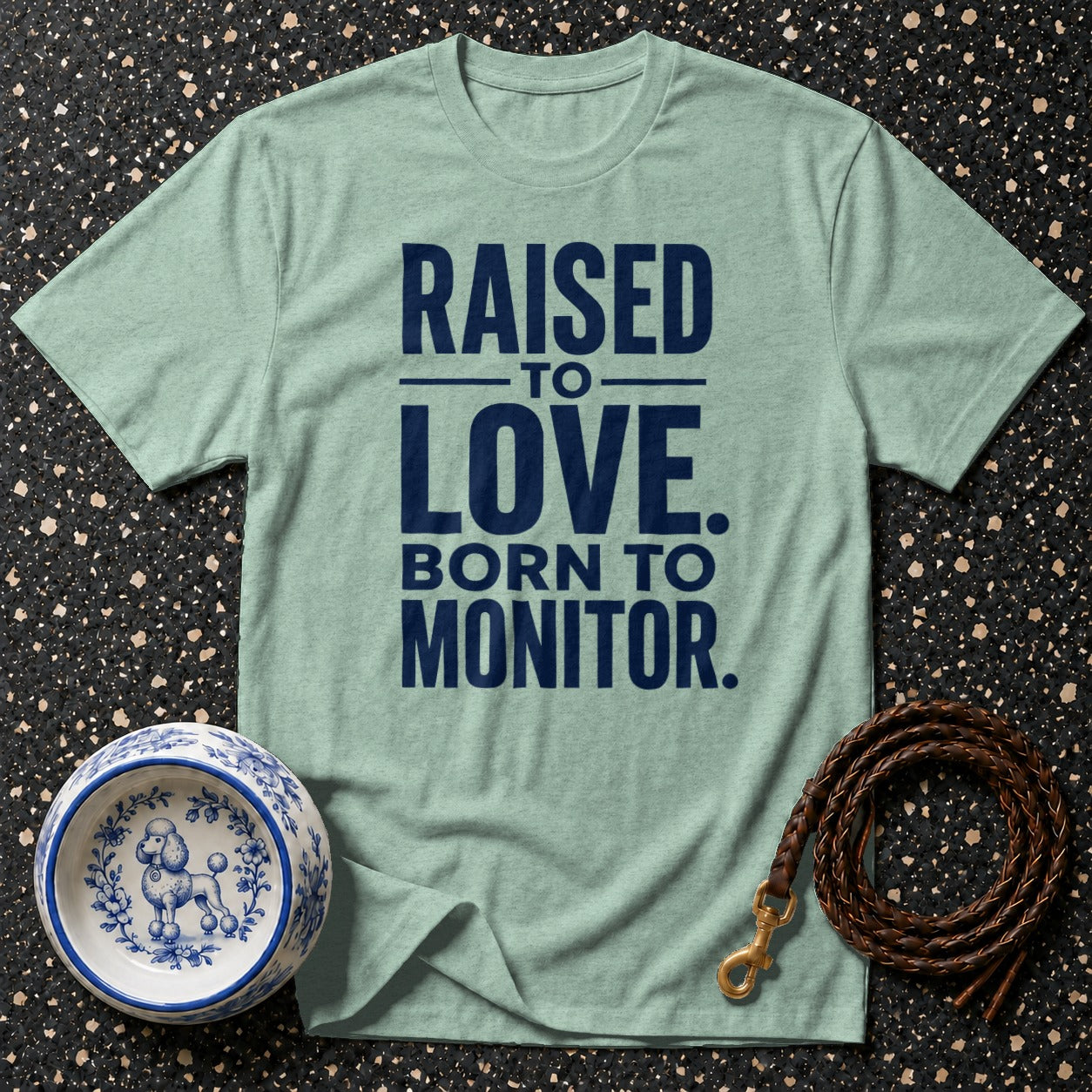 Light blue t-shirt with navy text: "RAISED TO LOVE. BORN TO MONITOR."