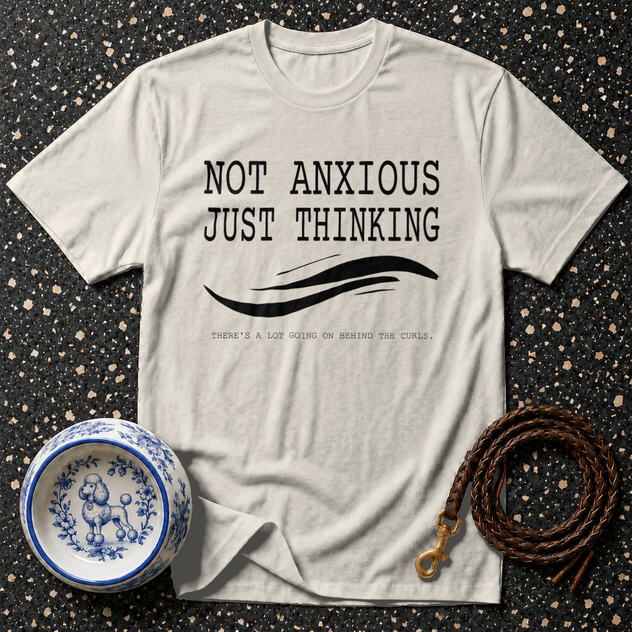 Cream t-shirt with black text: "NOT ANXIOUS JUST THINKING". Poodle bowl and leash nearby.