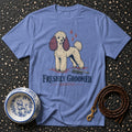 Blue t-shirt with a cream poodle graphic and text "FRESHLY GROOMED. BRIEFLY."