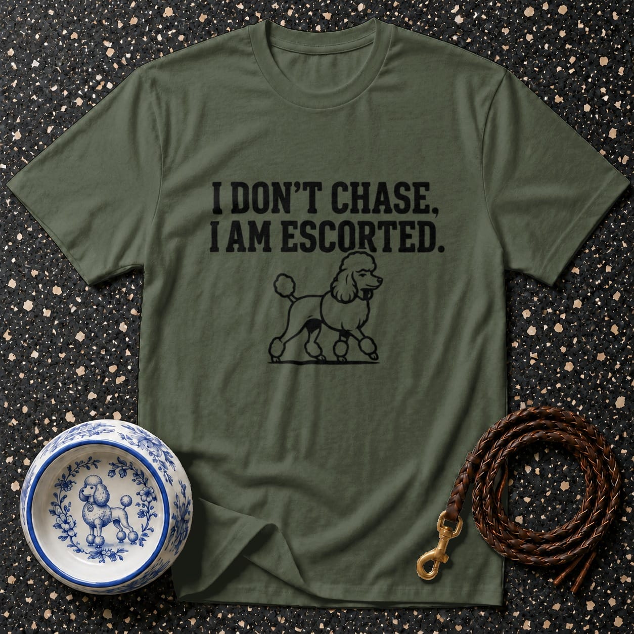 Olive t-shirt with black text "I DON'T CHASE, I AM ESCORTED" and poodle illustration.