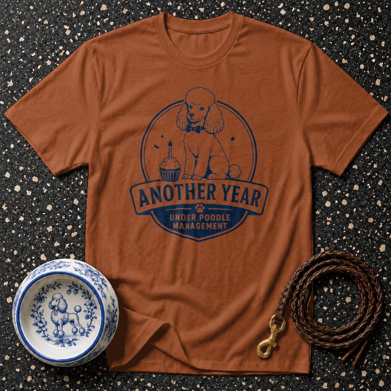 Brown t-shirt with blue poodle, cupcake, and text: "Another Year Under Poodle Management".