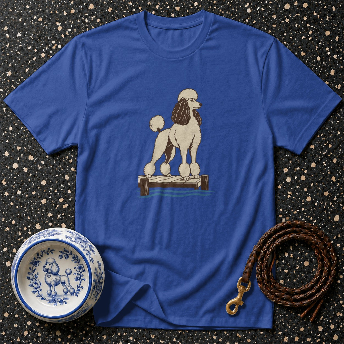 Blue t-shirt with a drawing of a poodle on a dock, a dog bowl, and a leash.