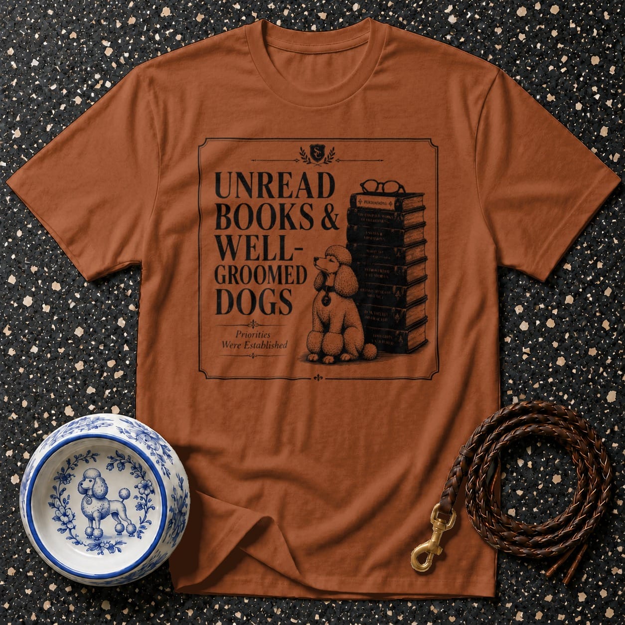 T-shirt graphic reads "Unread Books & Well-Groomed Dogs" with a poodle and stack of books.