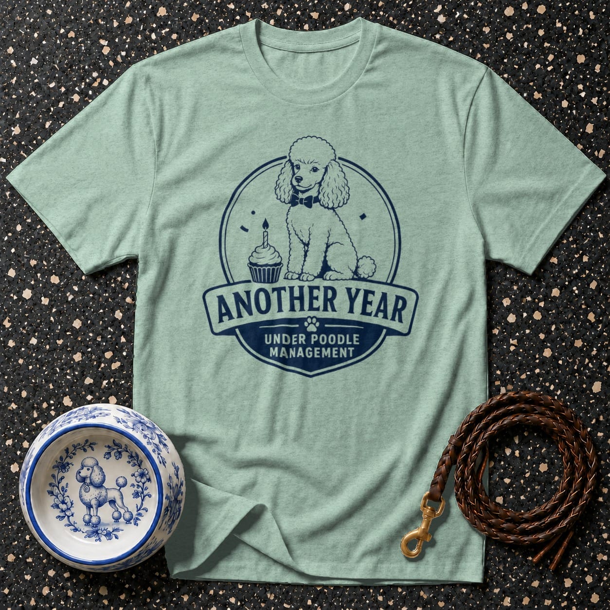 Mint t-shirt with navy graphic of a poodle and text: "Another Year Under Poodle Management."